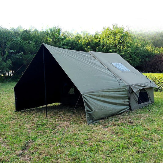 Green tent set up in a grassy area with trees in the background