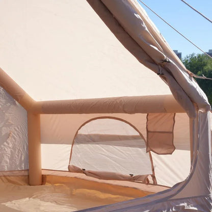 Partial view of a beige inflatable structure with mesh panels, set against a clear sky.