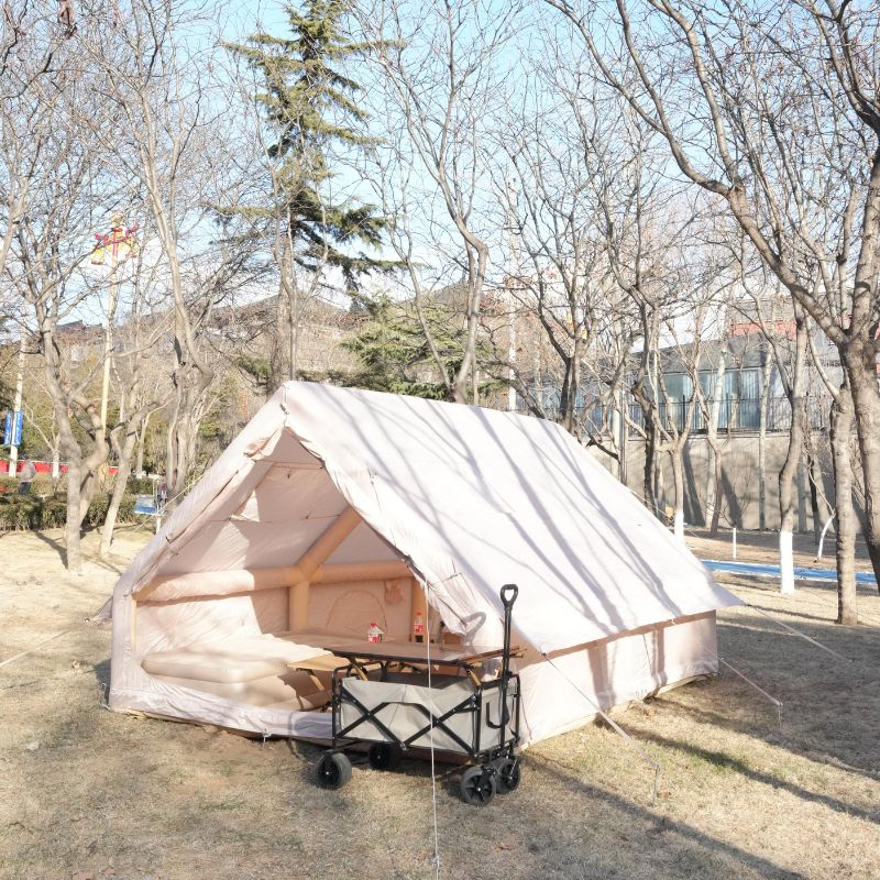 White tent with a cart in front, set up outdoors with trees and buildings in the background