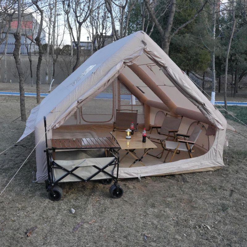 Camping tent with outdoor furniture and a cart in a park setting
