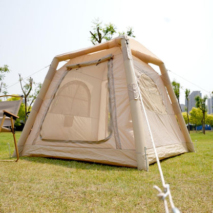 Beige camping tent with a chair on grassy area with trees and buildings in the background