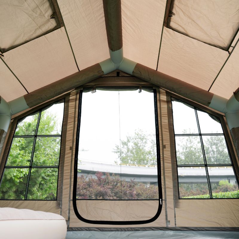 Interior of a tent with large windows showing greenery outside