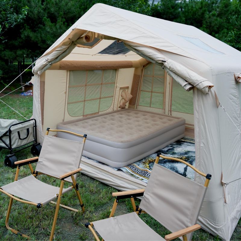 Camping setup with a tent, air mattress, and chairs outdoors.