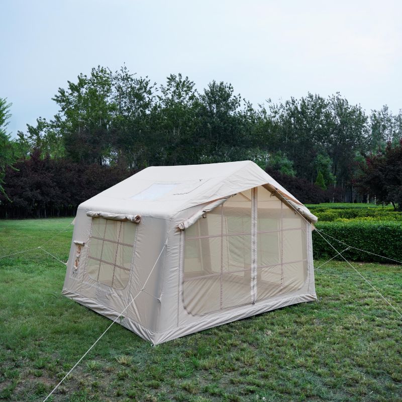 Beige camping tent with mesh sides on a grassy area with trees in the background