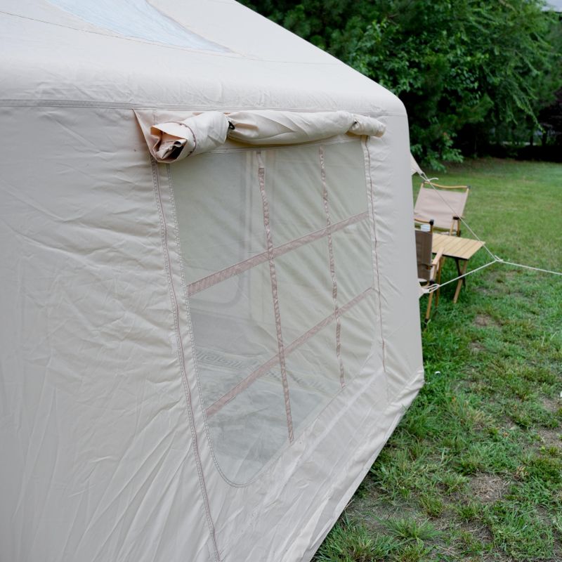 Beige tent with mesh side panel in a grassy outdoor setting
