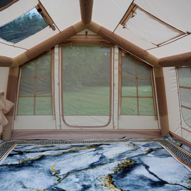 Interior of a tent with large windows and a blue patterned rug.