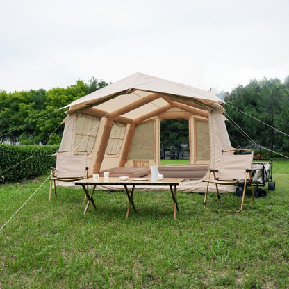 Large beige tent with wooden frame on grassy area with trees in the background