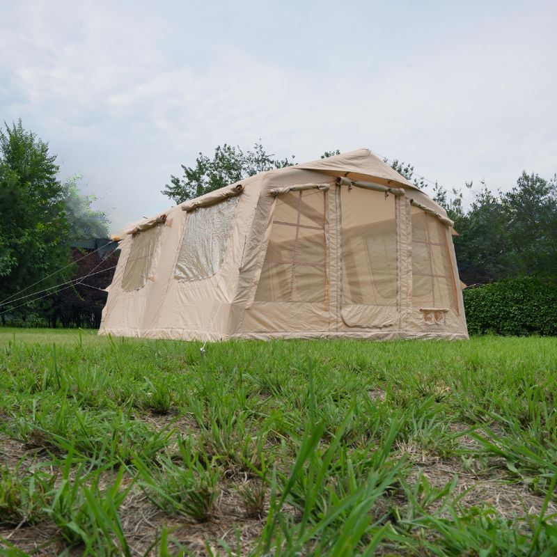 Beige camping tent with mesh windows on a grassy area with trees in the background
