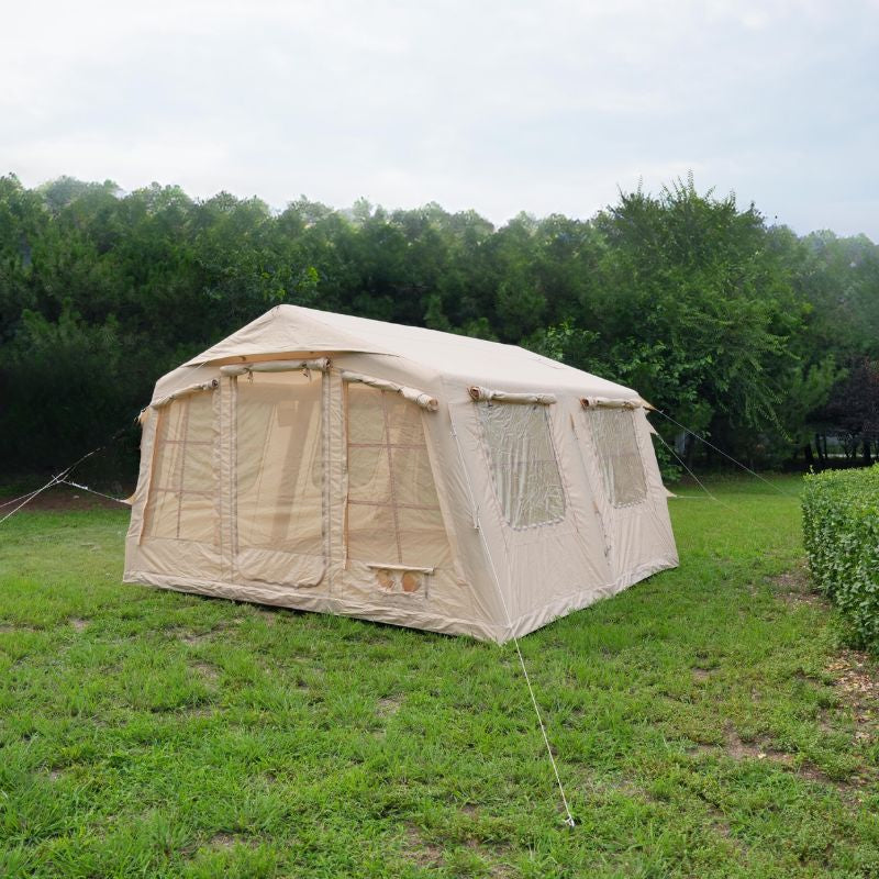 Beige camping tent with mesh windows on a grassy area with trees in the background