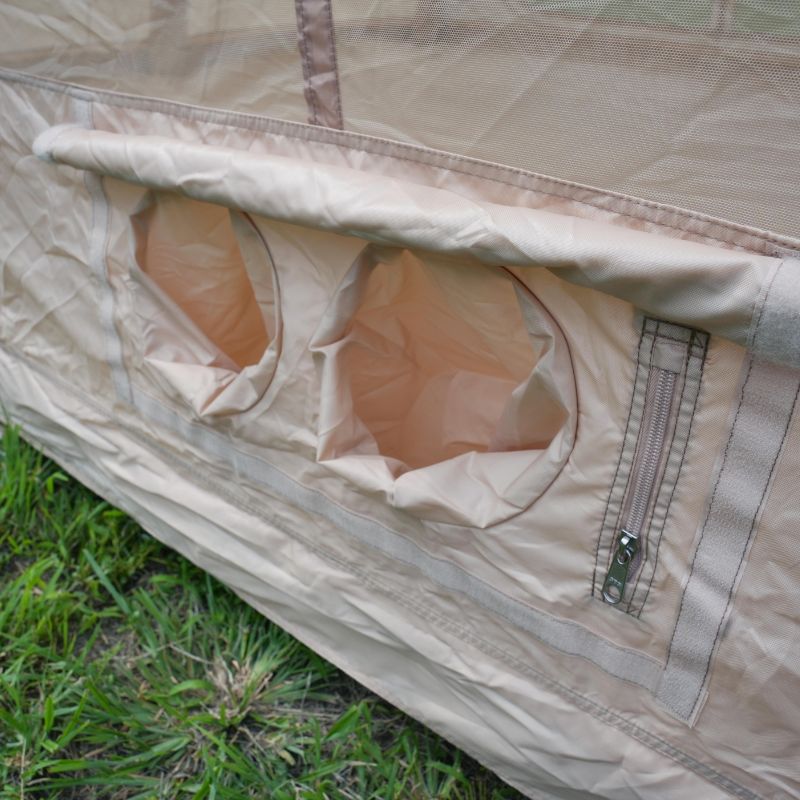 Close-up of a beige tent with mesh and zipper on grass