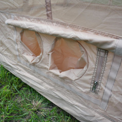 Close-up of a beige tent with mesh and zipper on grass