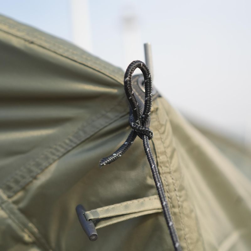 Close-up of a tent zipper with a cord lock on a beige tent background