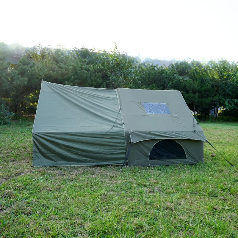 Green camping tent on grass with trees in the background