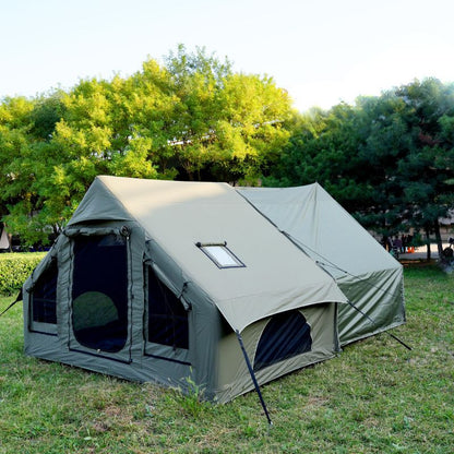 Green camping tent set up in a grassy area with trees in the background