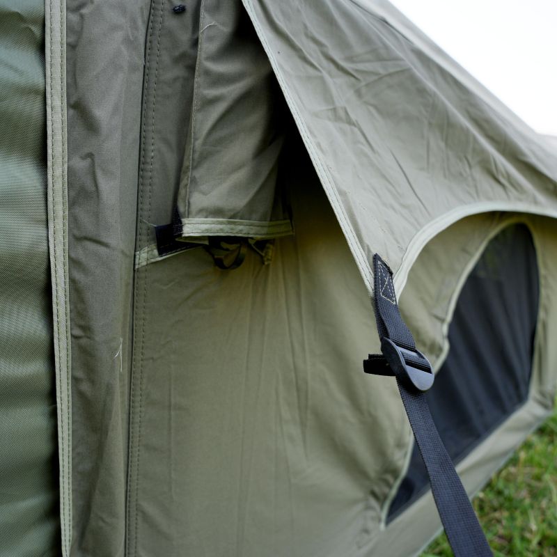 Close-up of a green tent with a strap and zipper, showing the interior.
