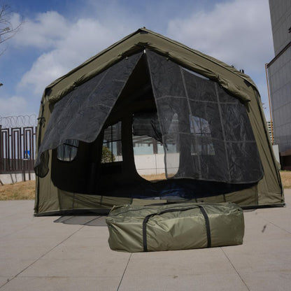 Green camping tent with mesh windows and a matching carrying bag on a paved surface.