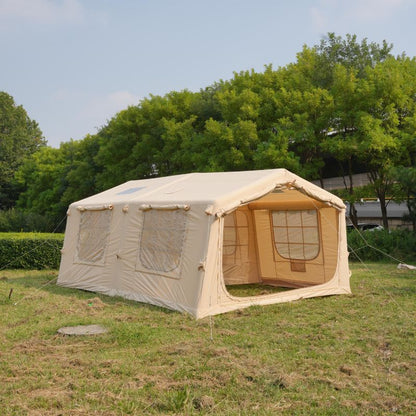 Beige camping tent with attached side room on grassy area with trees in the background