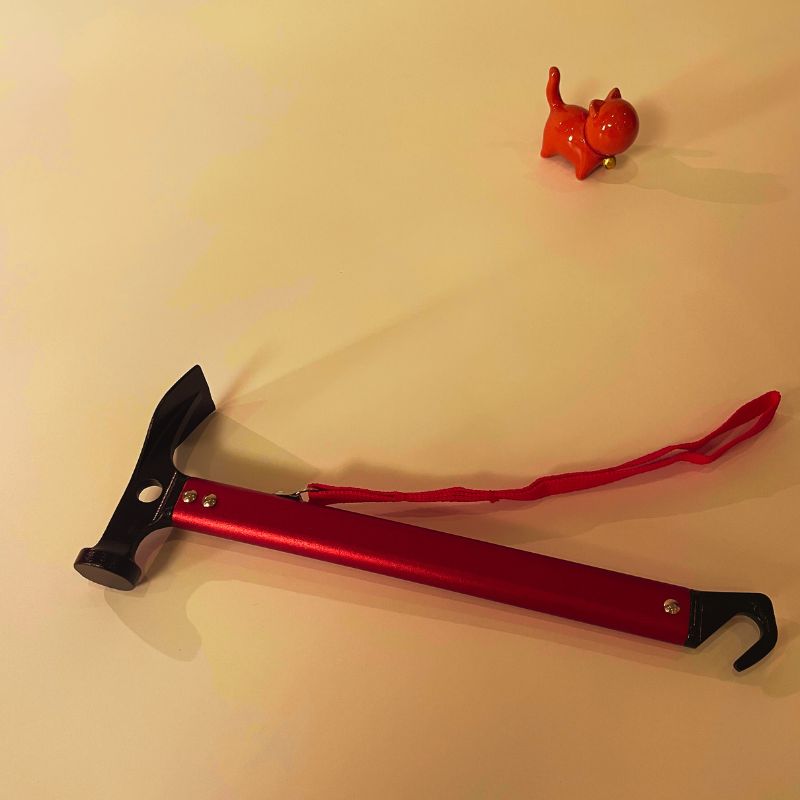 Red and black tool on a beige surface with a small red object in the background