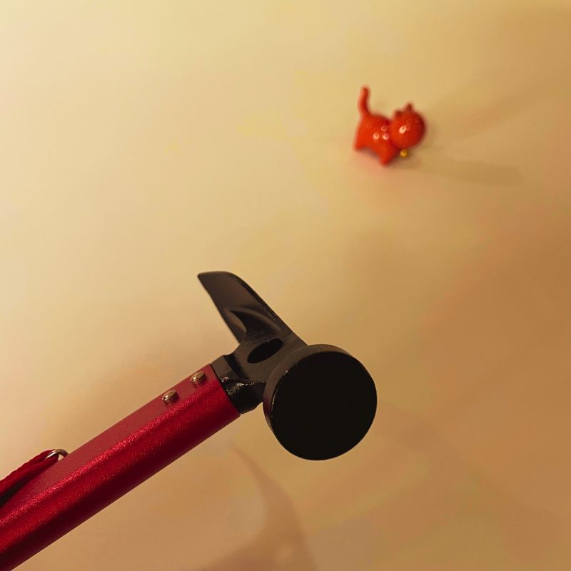 Red and black tool with a small red object on a beige background