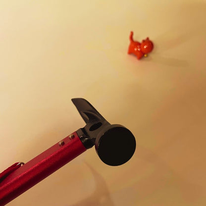 Red and black tool with a small red object on a beige background