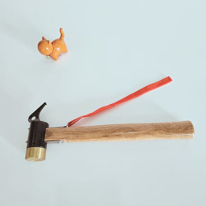 Small hammer with wooden handle and brass head on a light blue background