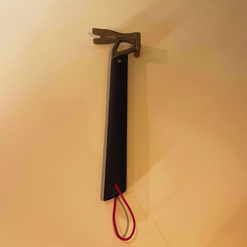 Tool with a black handle and red cord on a beige background