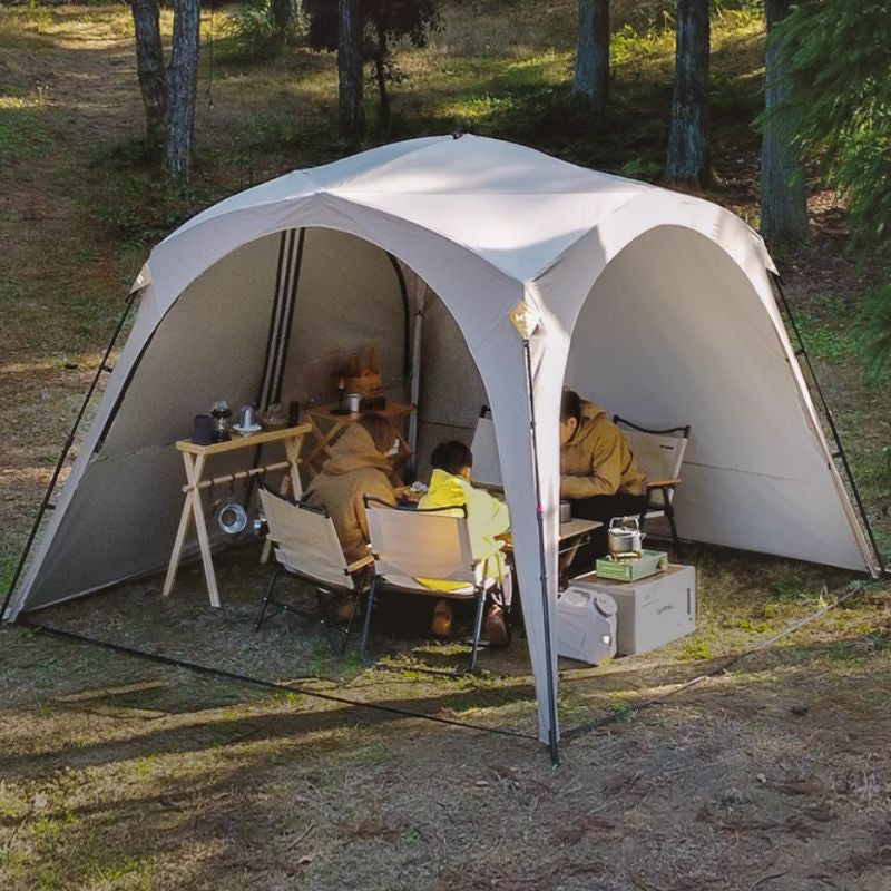 People sitting inside a large white tent in a forest setting