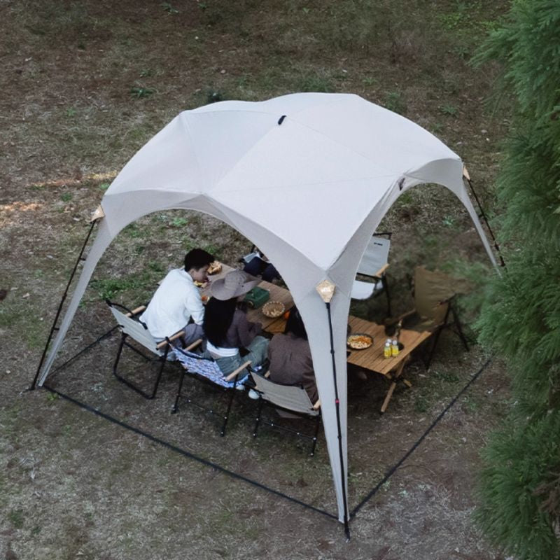 People sitting under a white canopy in a forest setting