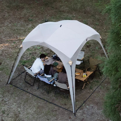 People sitting under a white canopy in a forest setting