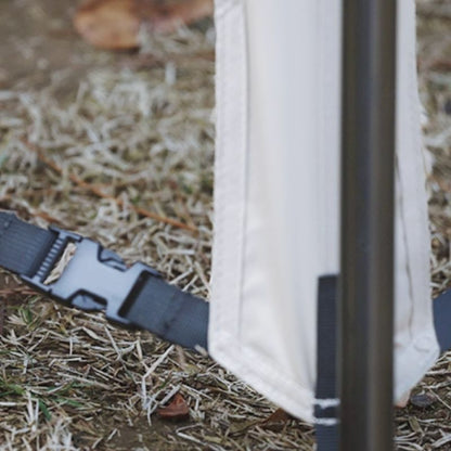 Close-up of a white bag with a black strap on a grassy ground.
