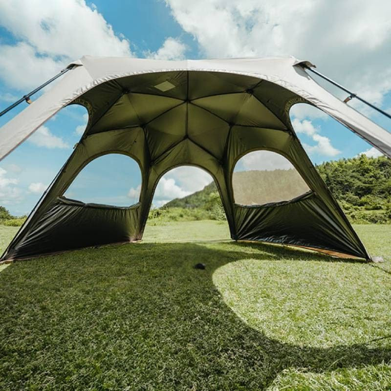 Large outdoor canopy tent set up on grass with a scenic background