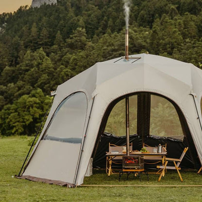Large dome-shaped tent with a table and chairs set up outdoors in a forested area.