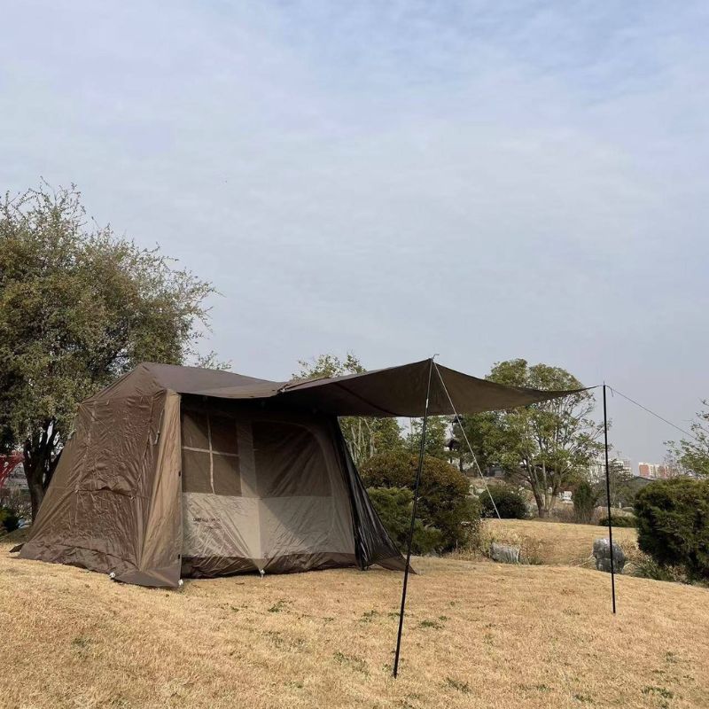 Tent with an extended awning on a grassy area with trees in the background