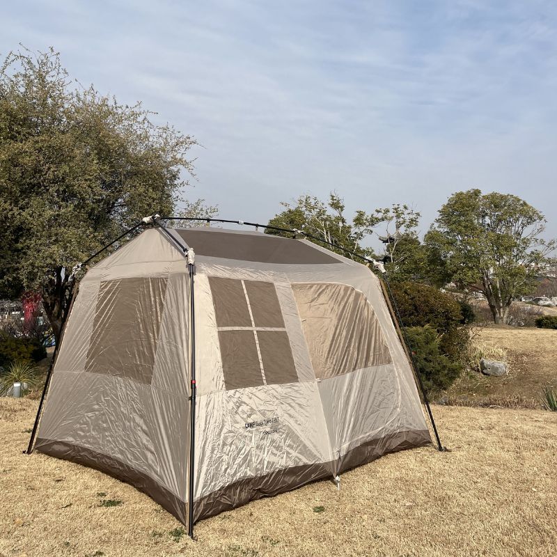 Screened tent with mesh walls on a grassy area with trees in the background