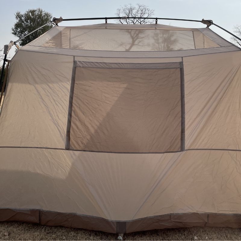 Beige camping tent with mesh windows on a clear day