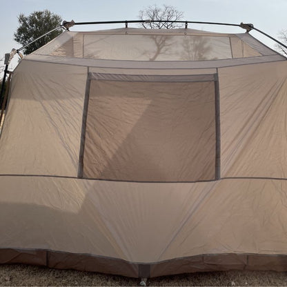 Beige camping tent with mesh windows on a clear day