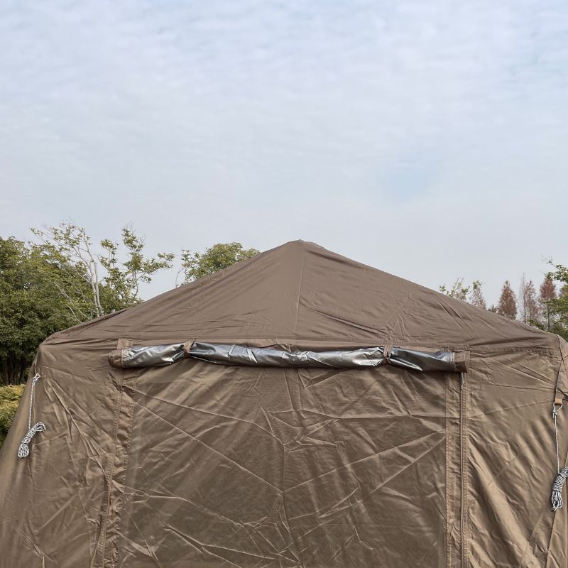Brown tent with a tarpaulin covering it against a clear sky