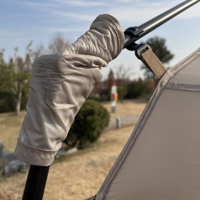 Close-up of a gloved hand adjusting a tent pole with a blurred outdoor background