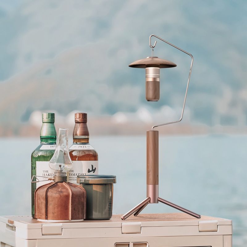 Camping lantern with bottles on a cooler by a scenic lake
