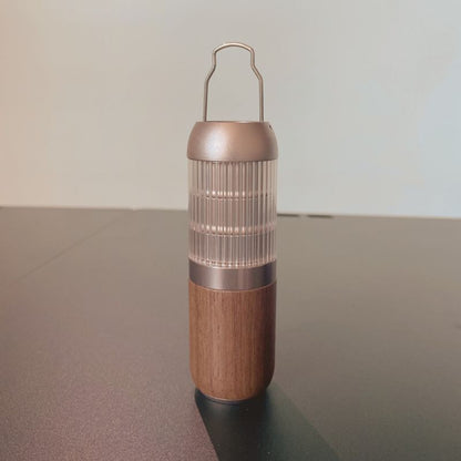 Tall cylindrical container with wooden base and metallic top on a reflective surface