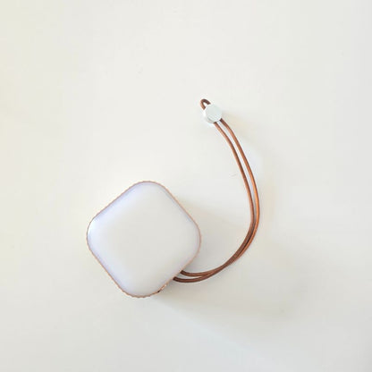 White square object with a brown strap on a light beige background