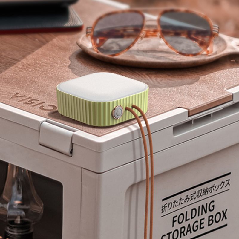 Green electronic device on a folding storage box with sunglasses in the background