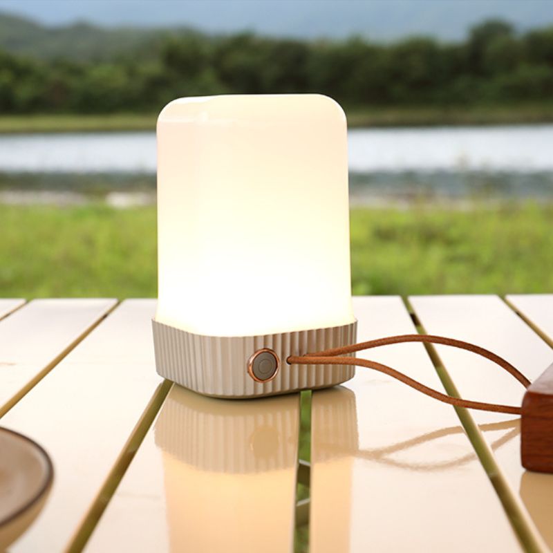 White camping lantern on a wooden table with a natural background