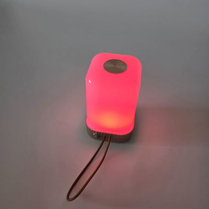 Pink portable light with a brown strap on a gray background