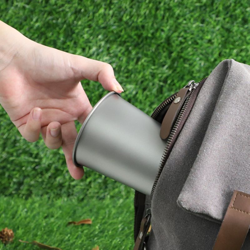 Person holding a silver cup with grass in the background