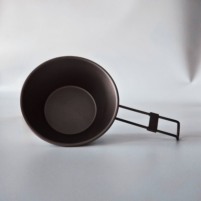 Black camping pot with handle on a white background