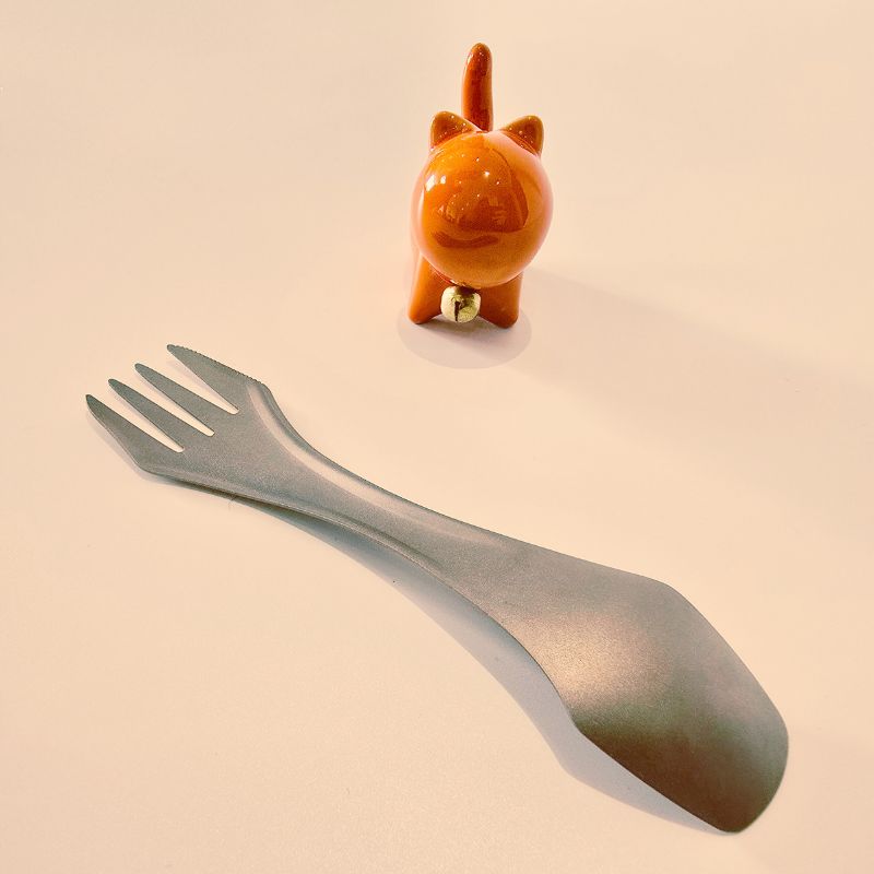 Metallic fork and small orange figurine on a beige background