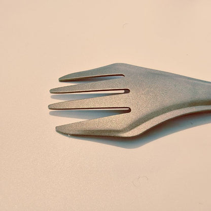 Green plastic fork on a beige background
