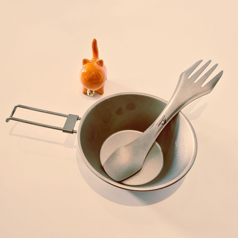 The camping cutlery set includes a pot, spoon, and fork, with a light-colored background.