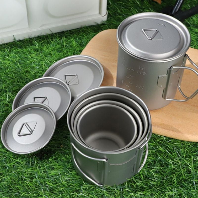 Set of metal camping mugs on grass
